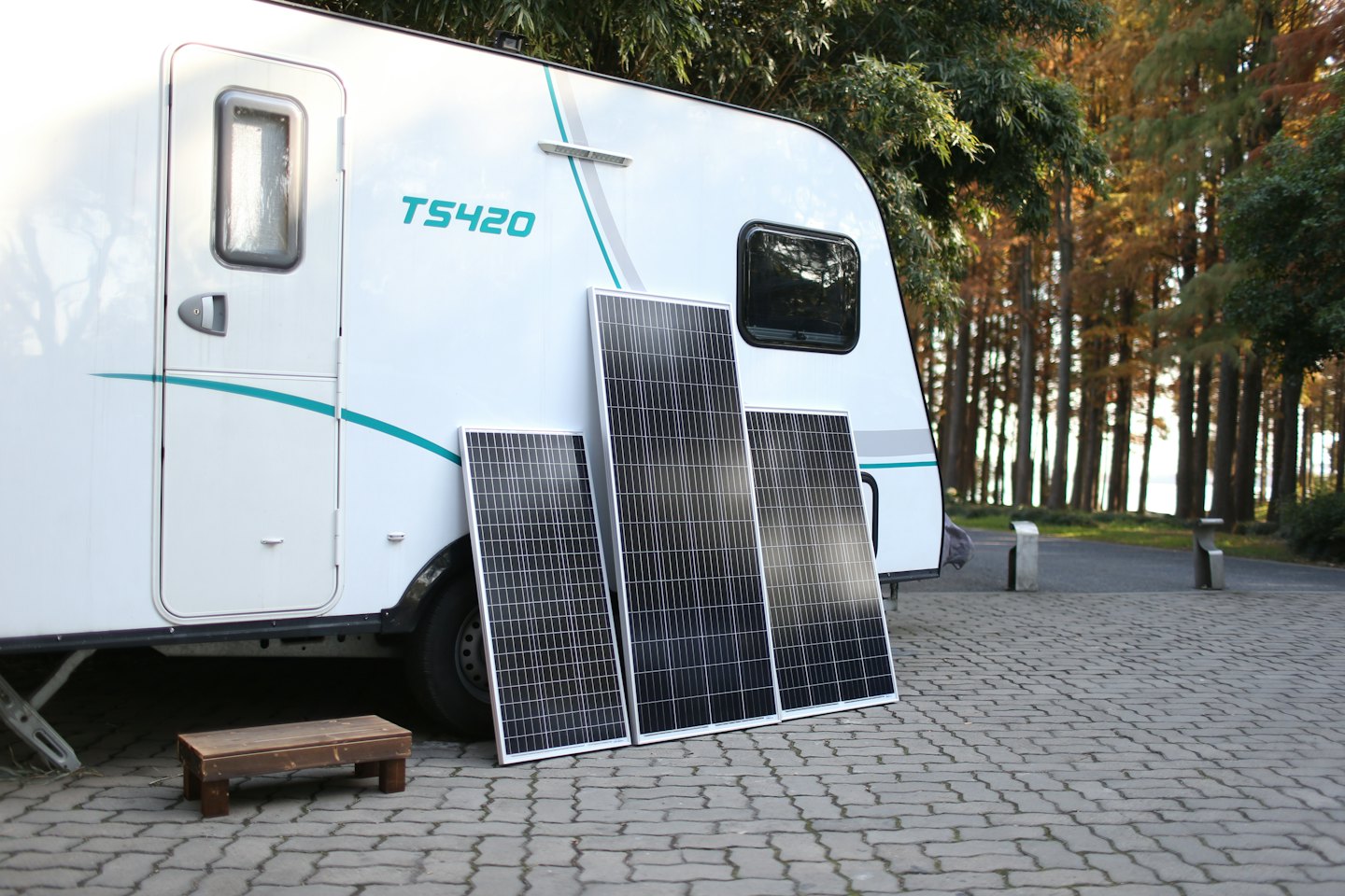 Drei Solarmodule lehnen an einem gestreiften Wohnwagen.